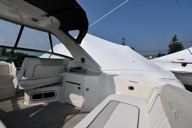 Slide: The Image of 2011 Sea Ray 310 Sundancer boat interior with seating and helm, under clear blue sky. - 18