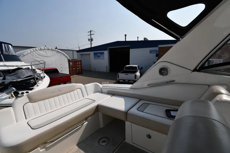 Slide: The Image of 2011 Sea Ray 310 Sundancer interior with white seating, docked near a warehouse. - 22