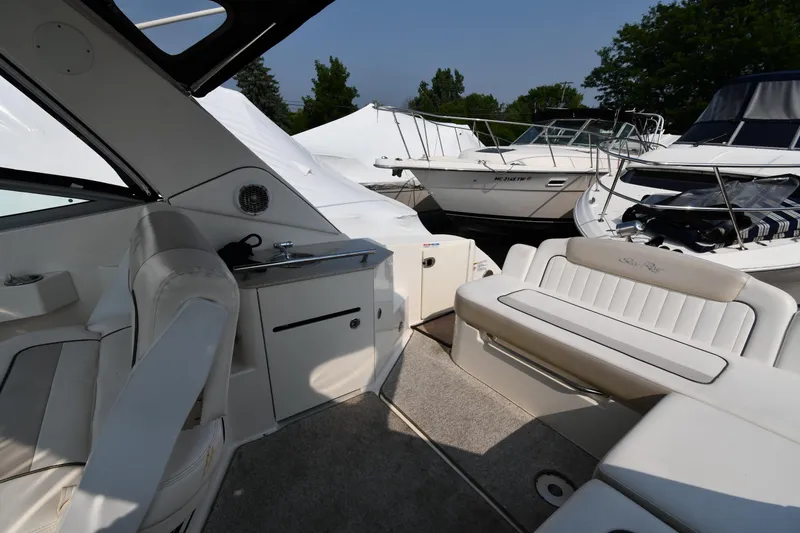 Slide: The Image of 2011 Sea Ray 310 Sundancer boat interior with seating and kitchenette, docked alongside other boats. - 23