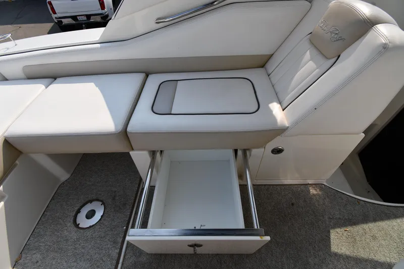 Slide: The Image of 2011 Sea Ray 310 Sundancer interior with open storage drawer and cushioned seating. - 28
