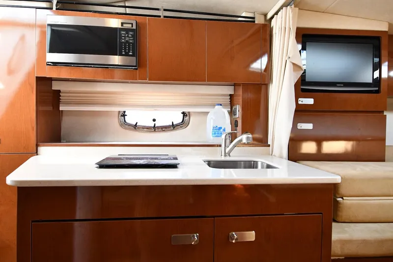 Slide: The Image of 2011 Sea Ray 310 Sundancer interior kitchen with sink, microwave, and TV. - 47