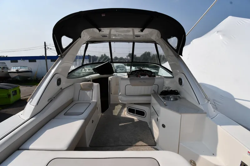 Slide: The Image of 2011 Sea Ray 310 Sundancer interior with seating, helm, and kitchenette under a canopy. - 8