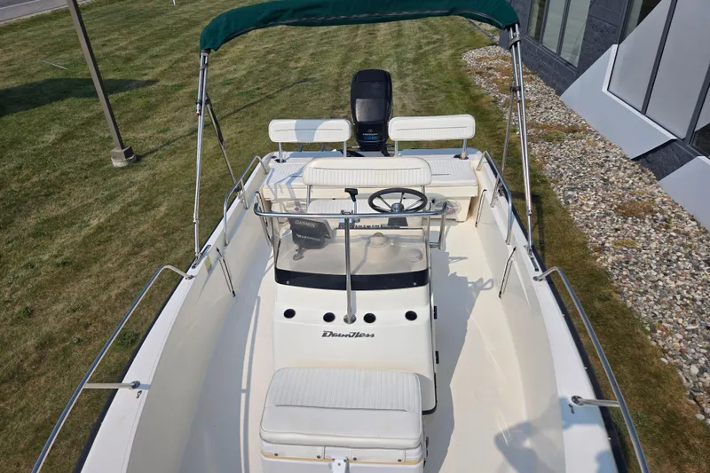 Slide: The Image of 1998 Boston Whaler 18 Dauntless boat with canopy, steering console, and seating on grassy area. - 8