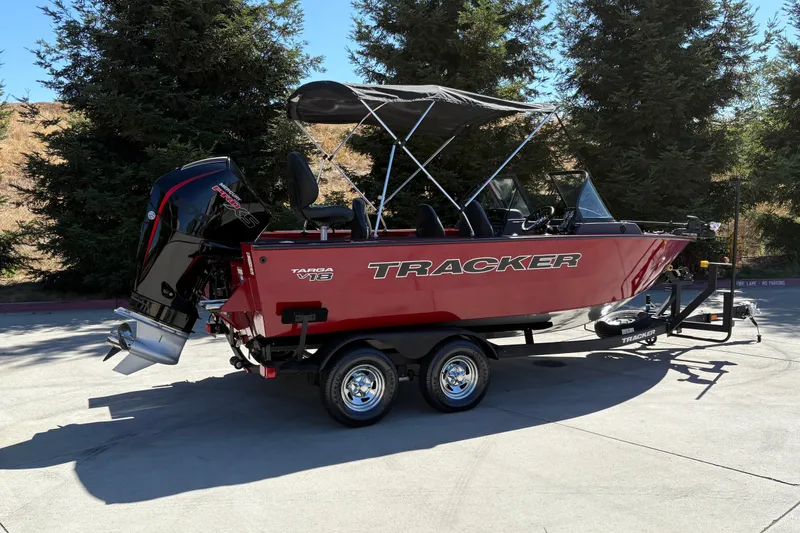 Slide: The Image of 2026 Tracker Targa V-18 WT boat on trailer, parked outdoors with trees in background. - 4