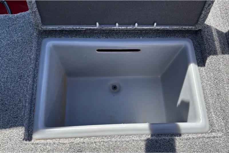 Slide: The Image of Livewell compartment in 2026 Tracker Targa V-18 WT boat, featuring gray interior and carpeted edges. - 43