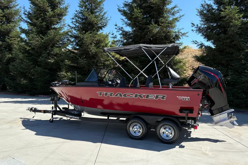 Slide: The Image of 2026 Tracker Targa V-18 WT boat on trailer, parked outdoors with trees in background. - 5