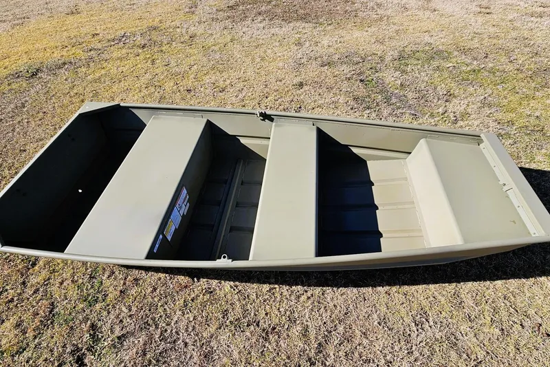 Slide: The Image of 2026 Tracker Grizzly 10 Jon boat on grassy terrain, showcasing its sturdy design. - 2