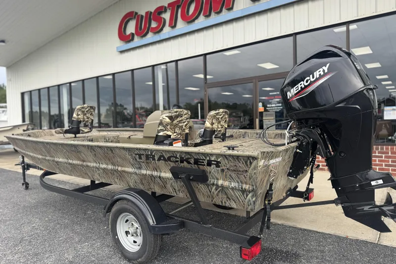 Slide: The Image of 2026 Tracker Grizzly 1754 SC boat with Mercury engine, camo design, outside dealership. - 31