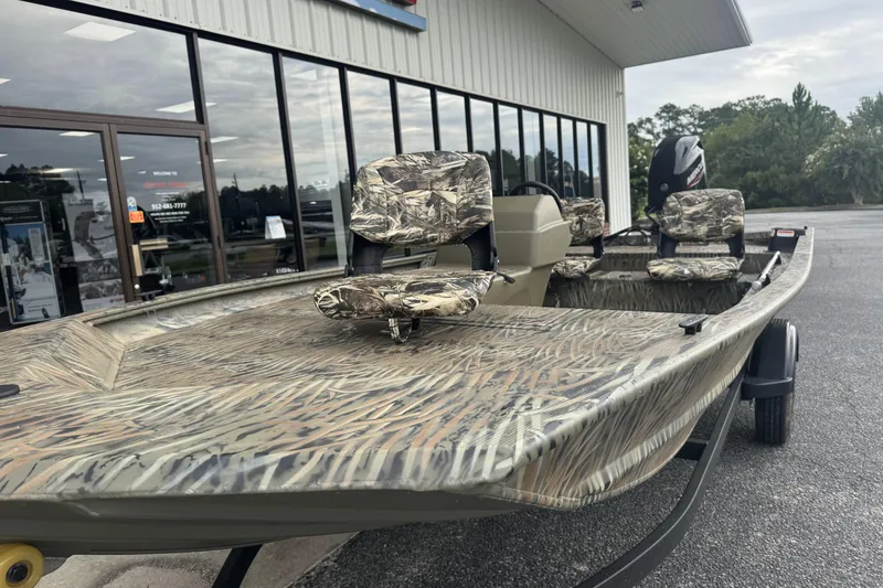 Slide: The Image of 2026 Tracker Grizzly 1754 SC boat with camouflage seats, parked outside a building. - 38