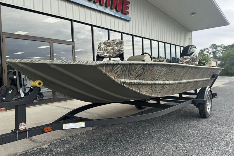 Slide: The Image of 2026 Tracker Grizzly 1754 SC boat on trailer, camo design, outside dealership. - 42