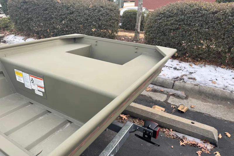 Slide: The Image of 2026 Tracker Grizzly 14 Jon boat on trailer, parked near snowy curb. - 4