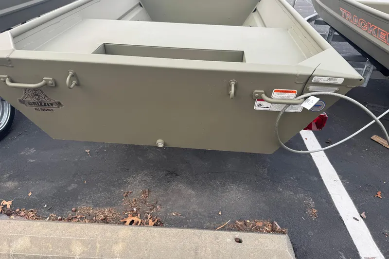 Slide: The Image of 2026 Tracker Grizzly 14 Jon boat, olive green, parked on asphalt. - 5