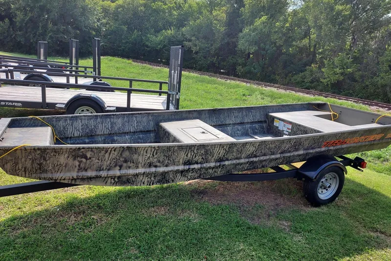 The Image of 2026 Tracker Grizzly 15 Jon boat on trailer, parked on grass with trees in background. - 0