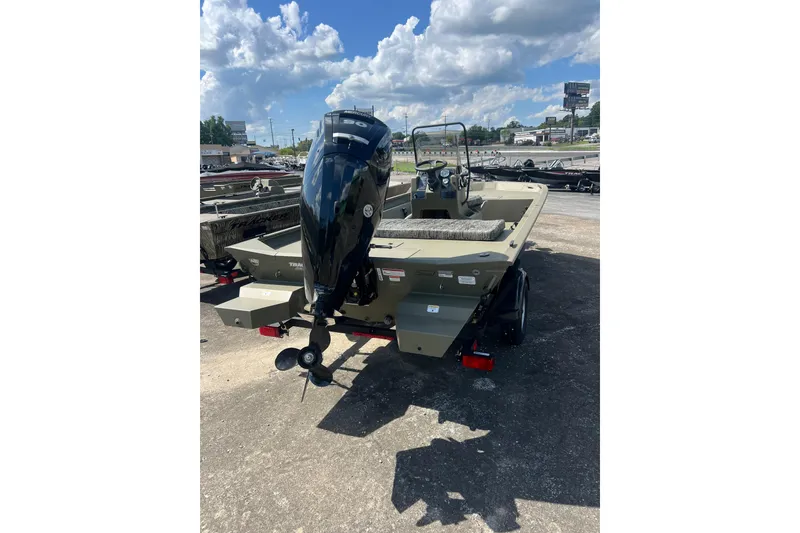 Slide: The Image of 2026 Tracker Grizzly 1860 CC boat with outboard motor, parked outdoors under a cloudy sky. - 10