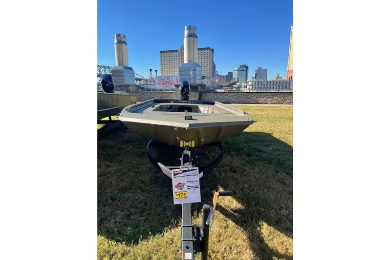 Slide: The Image of 2026 Tracker Grizzly 1654 T Sportsman boat on display outdoors with cityscape background. - 40