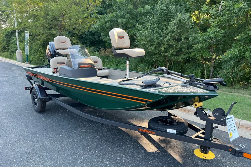 Slide: The Image of 2026 Tracker Bass Tracker Classic Limited boat on trailer, parked near lush greenery. - 2
