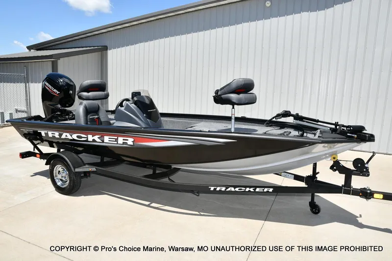 The Image of 2026 Tracker Pro Team 175 boat on trailer, parked outside a metal building. - 0