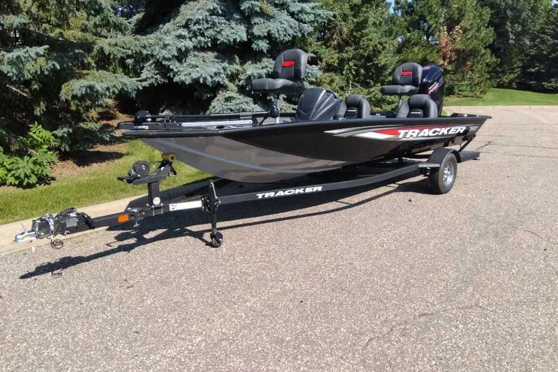 Slide: The Image of 2026 Tracker Pro Team 190 boat on trailer, parked outdoors, surrounded by trees. - 7