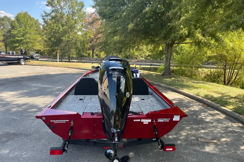Slide: The Image of 2026 Tracker Pro Team 175 boat with Mercury engine, parked outdoors, surrounded by trees. - 4