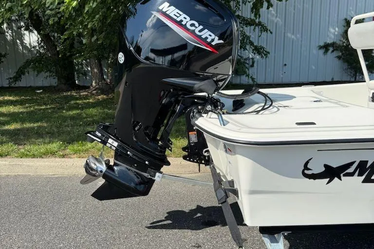 Slide: The Image of 2026 Mako Pro Skiff 17 CC with Mercury outboard motor, parked outdoors. - 2