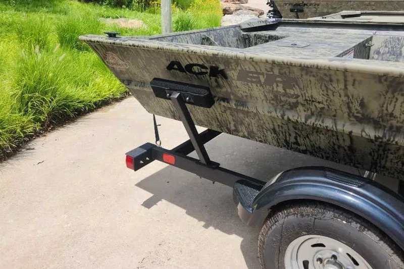 Slide: The Image of 2026 Tracker Grizzly 1860 Utility boat on trailer, parked on concrete near grass. - 4