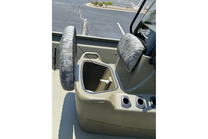 Slide: The Image of 2026 Tracker Grizzly 1860 Utility boat interior with open storage compartment and camo seat. - 14