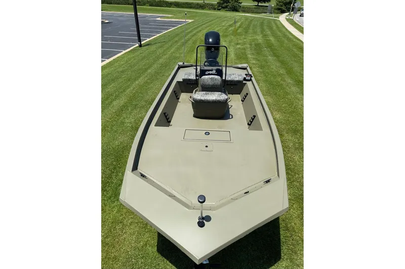 Slide: The Image of 2026 Tracker Grizzly 1860 Utility boat on grass, showcasing spacious deck and seating. - 12