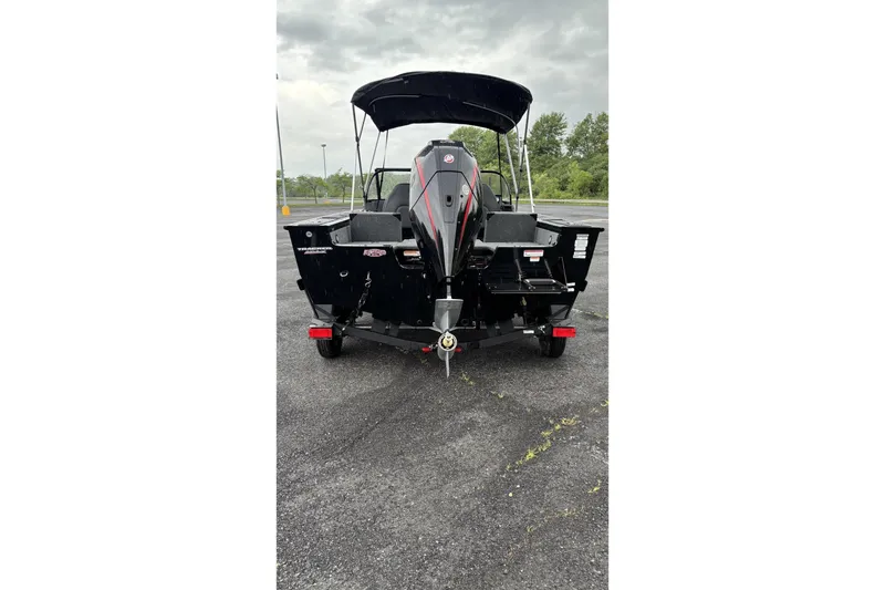 Slide: The Image of 2026 Tracker Targa V-18 Combo boat, rear view, parked on asphalt under cloudy sky. - 3