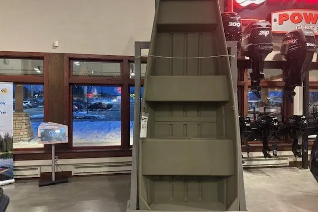 The Image of 2026 Tracker Grizzly 14 Jon boat displayed indoors, with outboard motors in the background. - 0