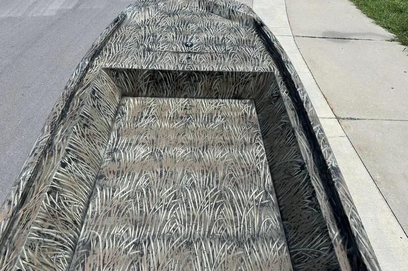 Slide: The Image of 2026 Tracker Grizzly 1648 Utility boat with camouflage pattern on a concrete surface. - 11