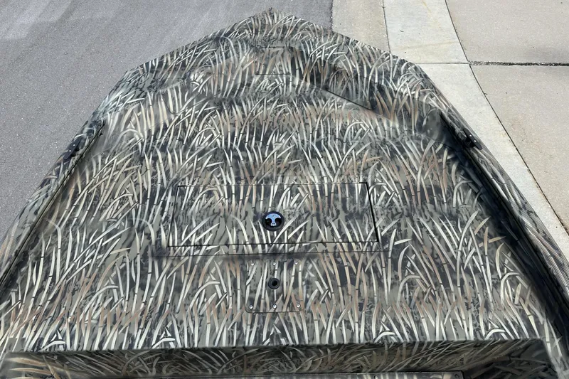 Slide: The Image of 2026 Tracker Grizzly 1648 Utility boat with camouflage pattern on pavement. - 12