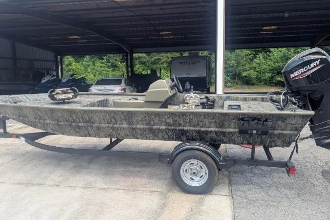 The Image of 2026 Tracker Grizzly 1754 SC boat on trailer, under covered storage, with Mercury outboard motor. - 0