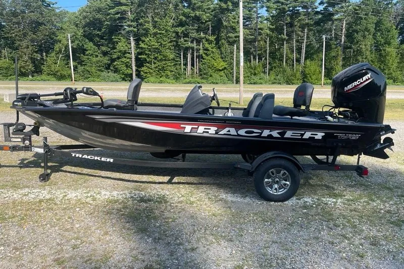 The Image of 2026 Tracker Pro Team 175 boat on trailer, parked outdoors with forest background. - 0