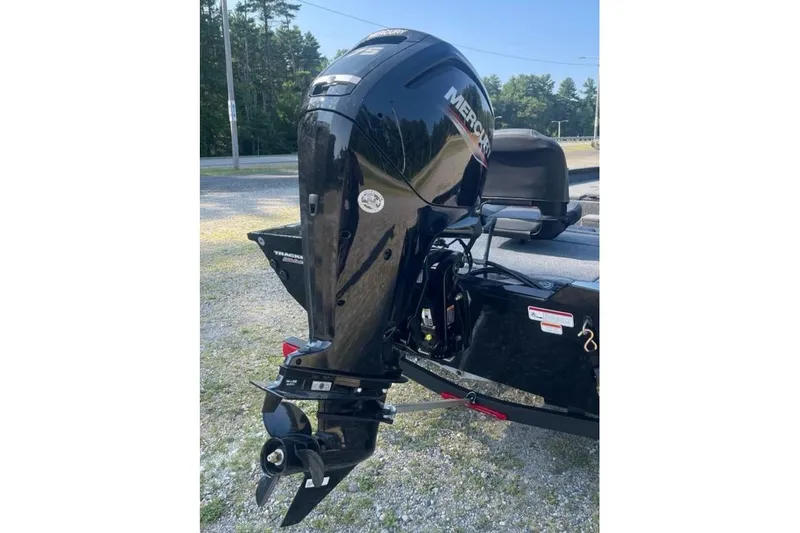 Slide: The Image of 2026 Tracker Pro Team 175 boat with Mercury outboard motor, parked on gravel. - 7