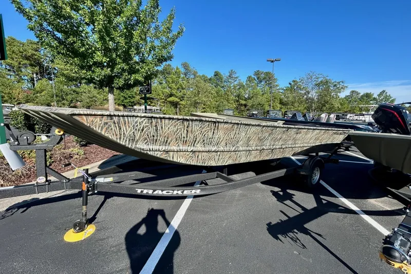 The Image of 2026 Tracker Grizzly 2072 Utility boat on trailer, camo design, parked outdoors. - 0