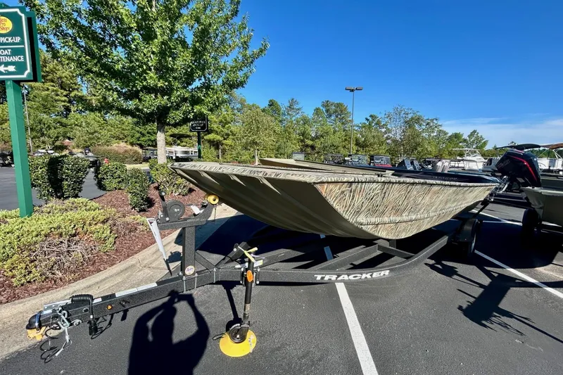 Slide: The Image of 2026 Tracker Grizzly 2072 Utility boat on trailer in parking lot, surrounded by trees. - 4