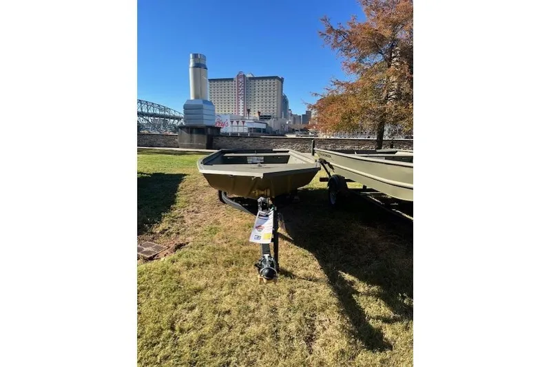 Slide: The Image of 2026 Tracker Grizzly 1648 Utility boat on grass, urban backdrop, sunny day. - 18