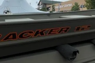 The Image of 2026 Tracker Grizzly 12 Jon boat on concrete, surrounded by trees and stone structures. - 0