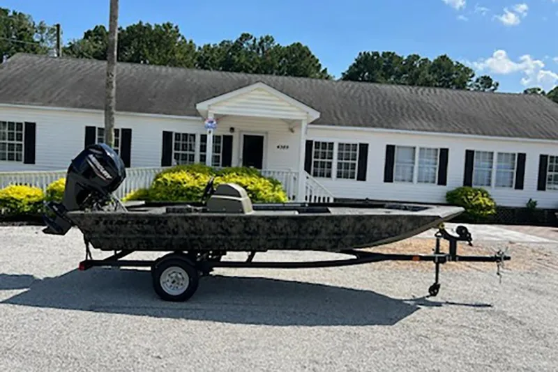The Image of 2026 Tracker Grizzly 1648 SC boat on trailer, parked in front of a white house. - 1