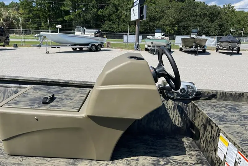 Slide: The Image of 2026 Tracker Grizzly 1648 SC boat console with steering wheel, parked outdoors. - 11