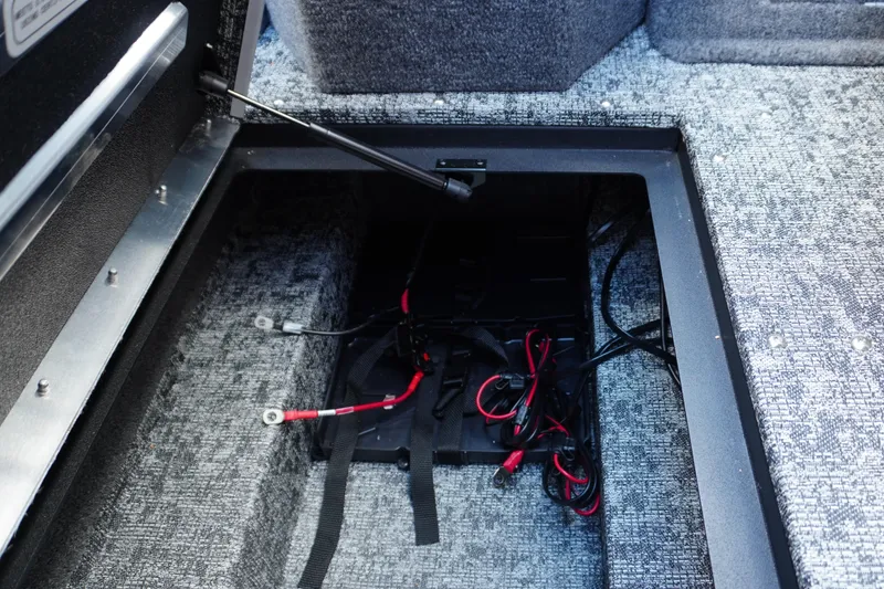 Slide: The Image of 2026 Tracker Targa V-18 WT boat battery compartment with wiring and carpeted interior. - 16