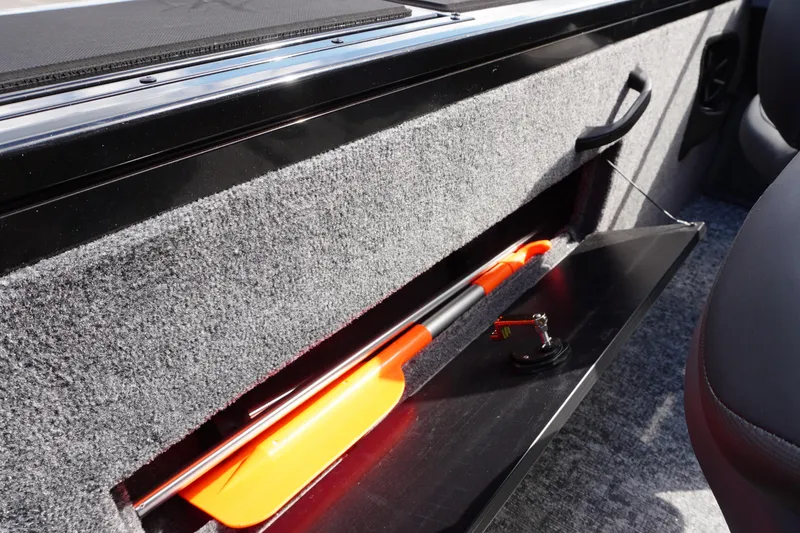 Slide: The Image of 2026 Tracker Targa V-18 WT boat storage compartment with orange paddle. - 26