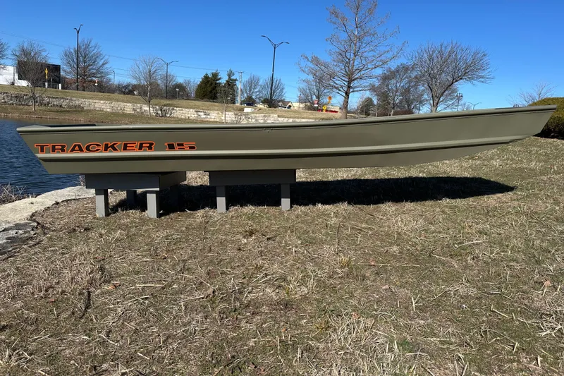 The Image of 2026 Tracker Grizzly 15 Jon boat displayed on grass near a pond. - 0