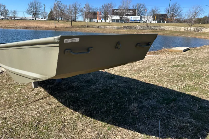 Slide: The Image of 2026 Tracker Grizzly 15 Jon boat by a lake, grassy shore, clear sky. - 2