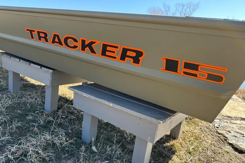 Slide: The Image of 2026 Tracker Grizzly 15 Jon boat displayed on wooden stands outdoors. - 5