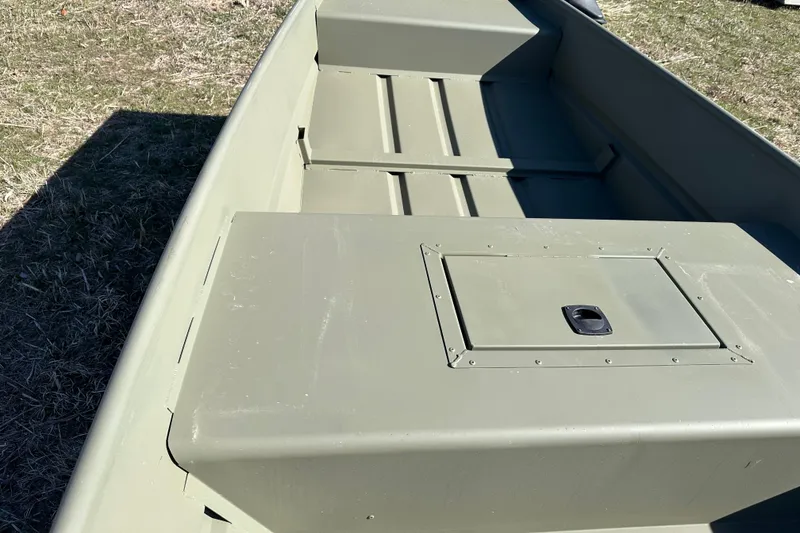 Slide: The Image of 2026 Tracker Grizzly 15 Jon boat interior with storage compartment, shown on grassy ground. - 6