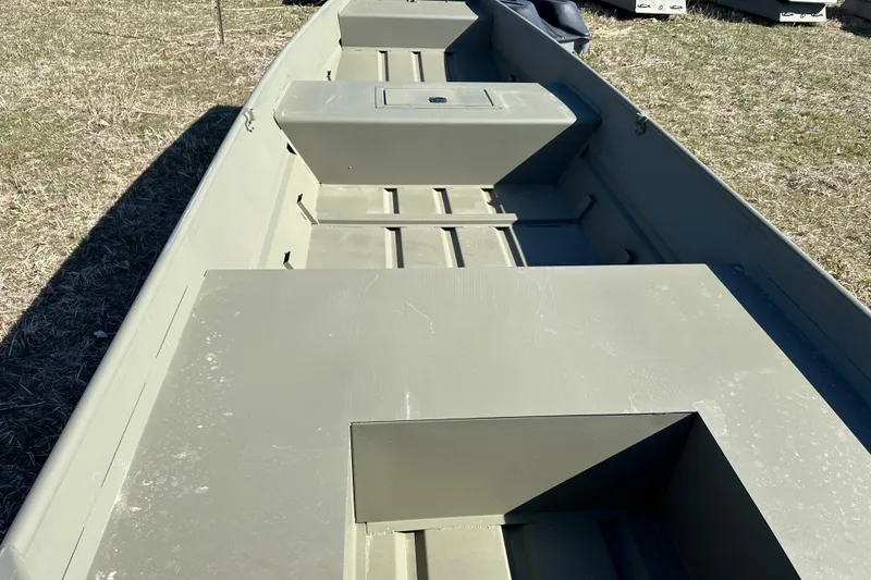 Slide: The Image of 2026 Tracker Grizzly 15 Jon boat interior, showcasing spacious seating and storage on grass. - 9