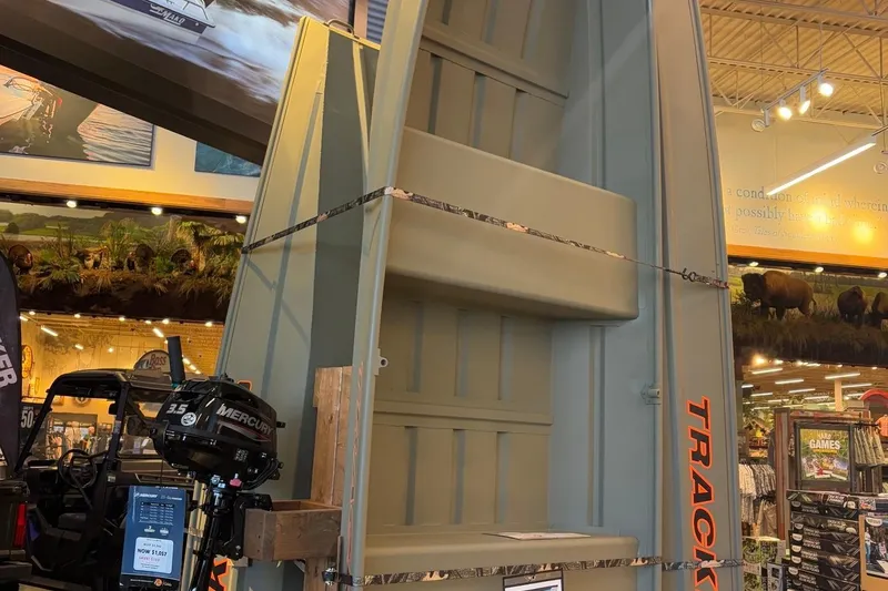 The Image of 2026 Tracker Grizzly 12 Jon boat displayed in a store with Mercury motor. - 0