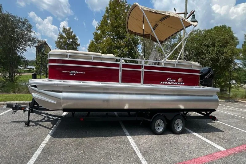 The Image of 2025 Sun Tracker Party Barge 24 DLX pontoon boat on trailer, parked outdoors. - 0