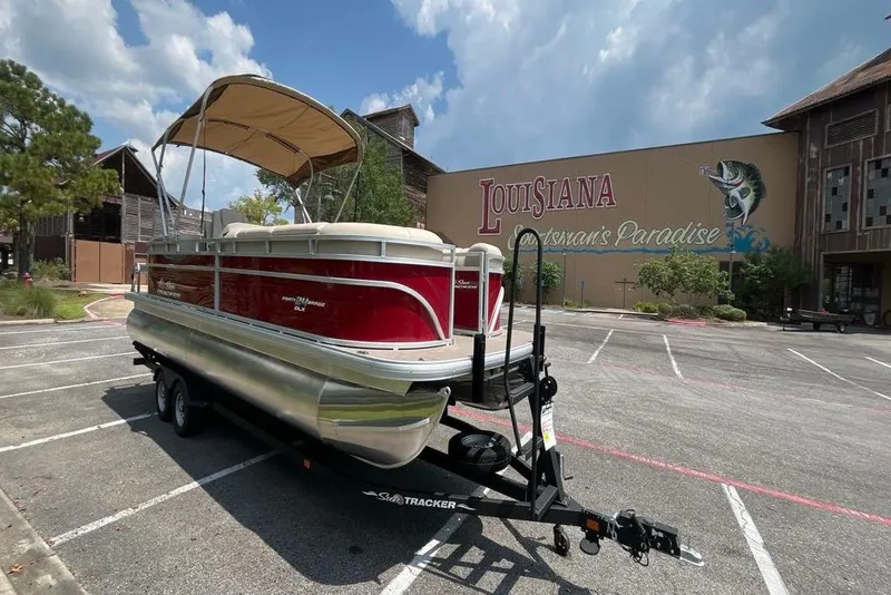Slide: The Image of 2025 Sun Tracker Party Barge 24 DLX pontoon boat in parking lot, Louisiana backdrop. - 5